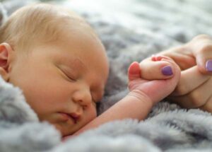 newborn baby holding finger