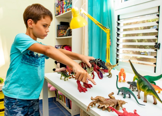 young boy playing with dinosaur figures; play therapy