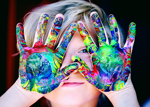 young child in play therapy with fingerpaint on hands