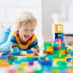 young boy playing with building blocks on floor; play therapy