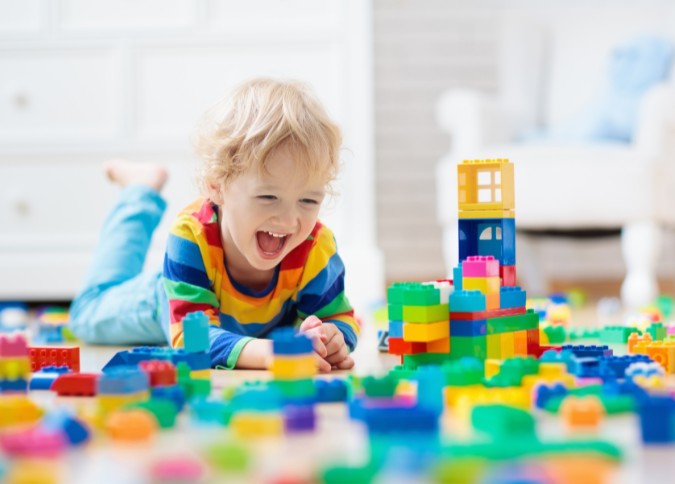 young boy playing with building blocks on floor; play therapy