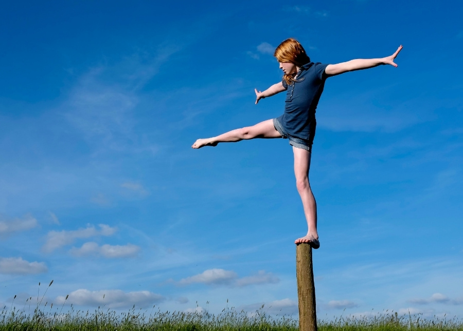 girl balancing on log with one foot extended