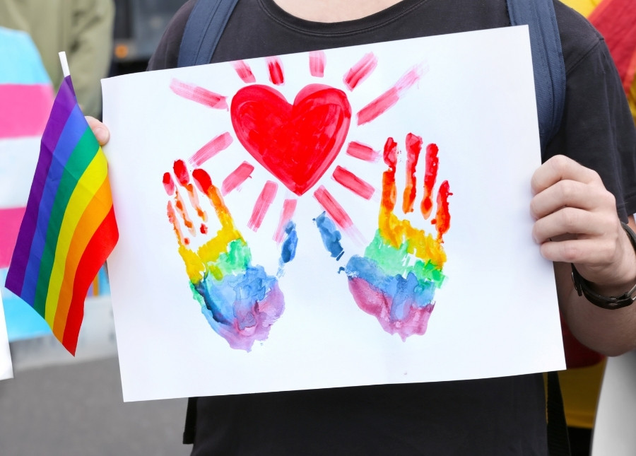person celebrating lgbtq community in parade, holding a pride flag and a drawing