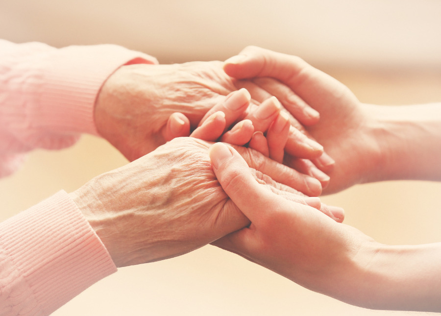 caregiver stress - caregiver holding hands with aging adult