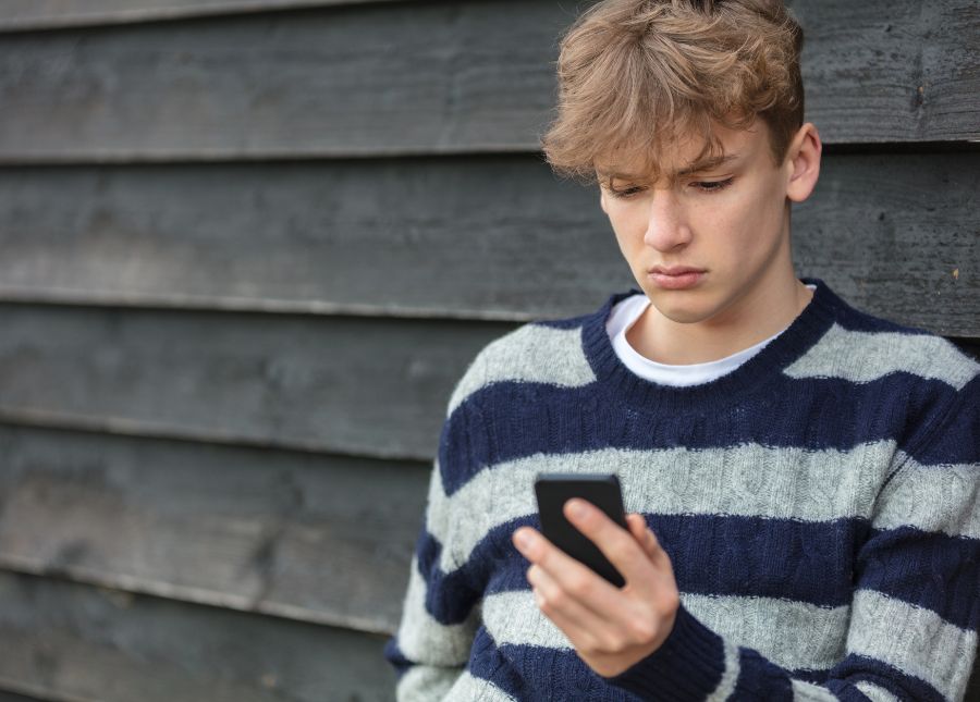 young, distressed person looking at a phone